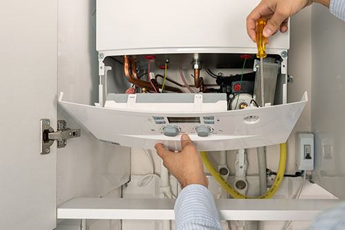 Heating technician repairing a residential boiler in Manhattan Beach