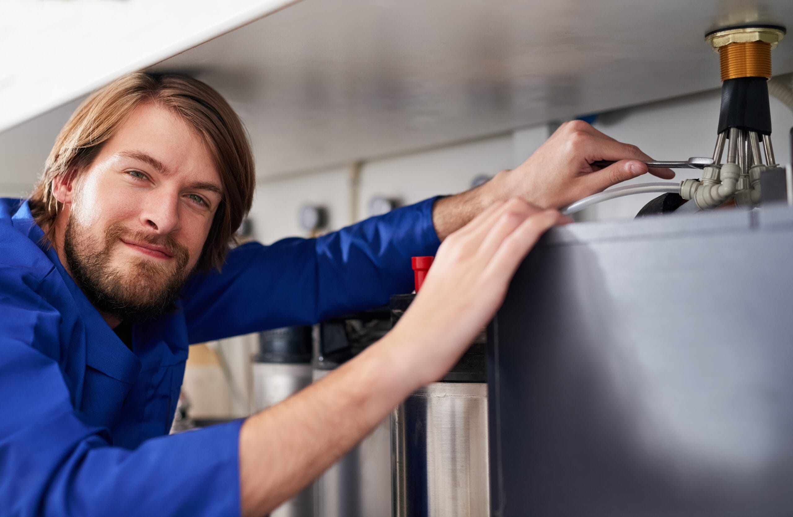 Technician servicing a residential water heater tank in Manhattan Beach
